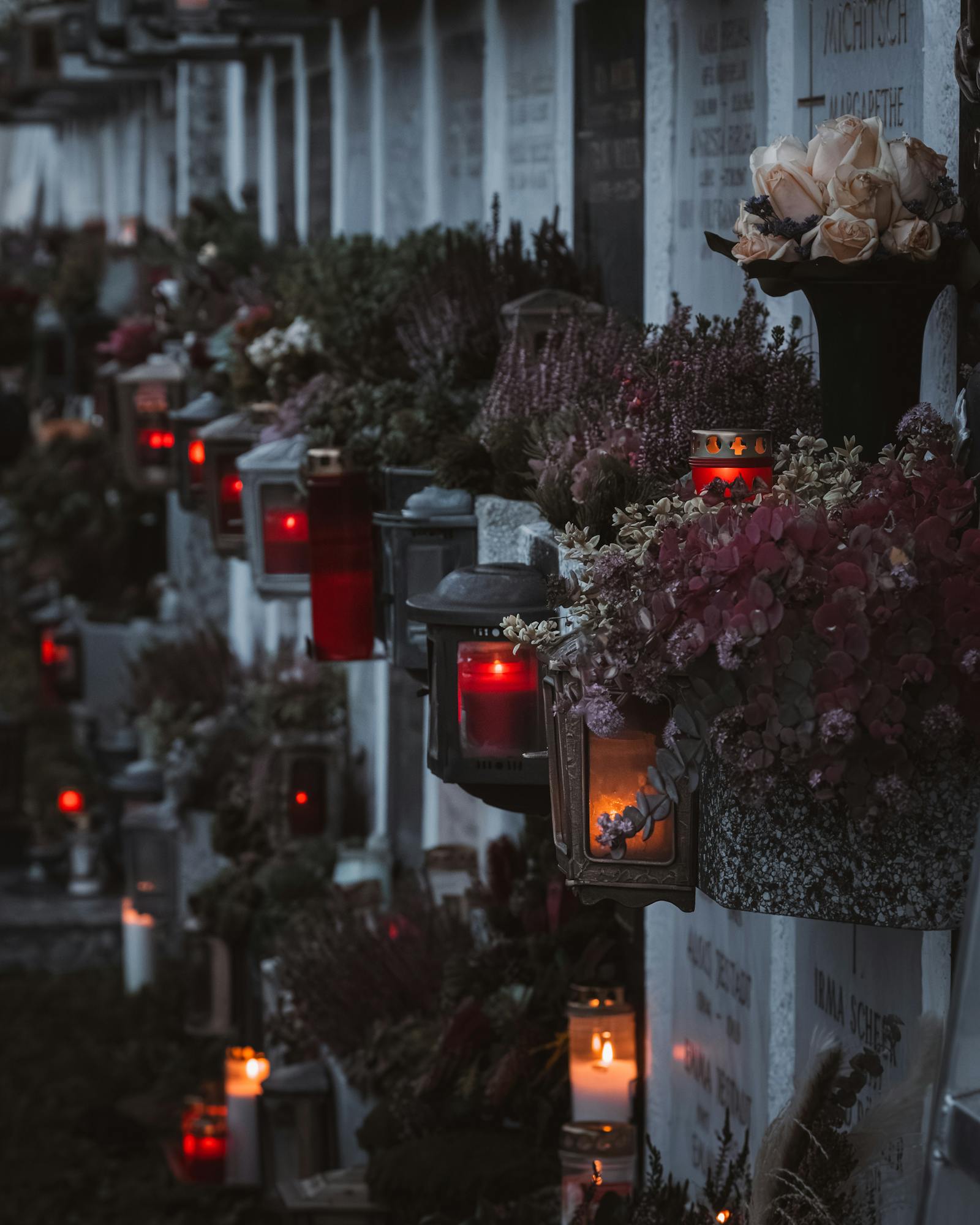 Peaceful cemetery scene with candles and flowers in Graz, Austria during twilight.