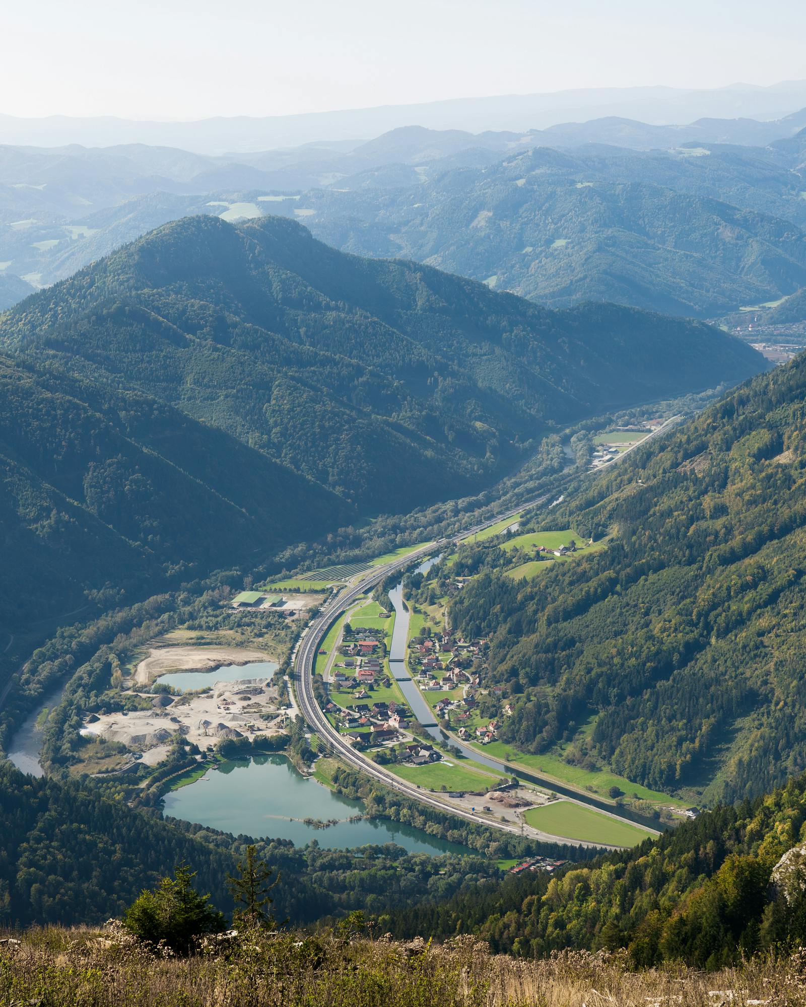 Beautiful aerial view of Röthelstein village nestled in the lush Styrian hills with clear skies and greenery.