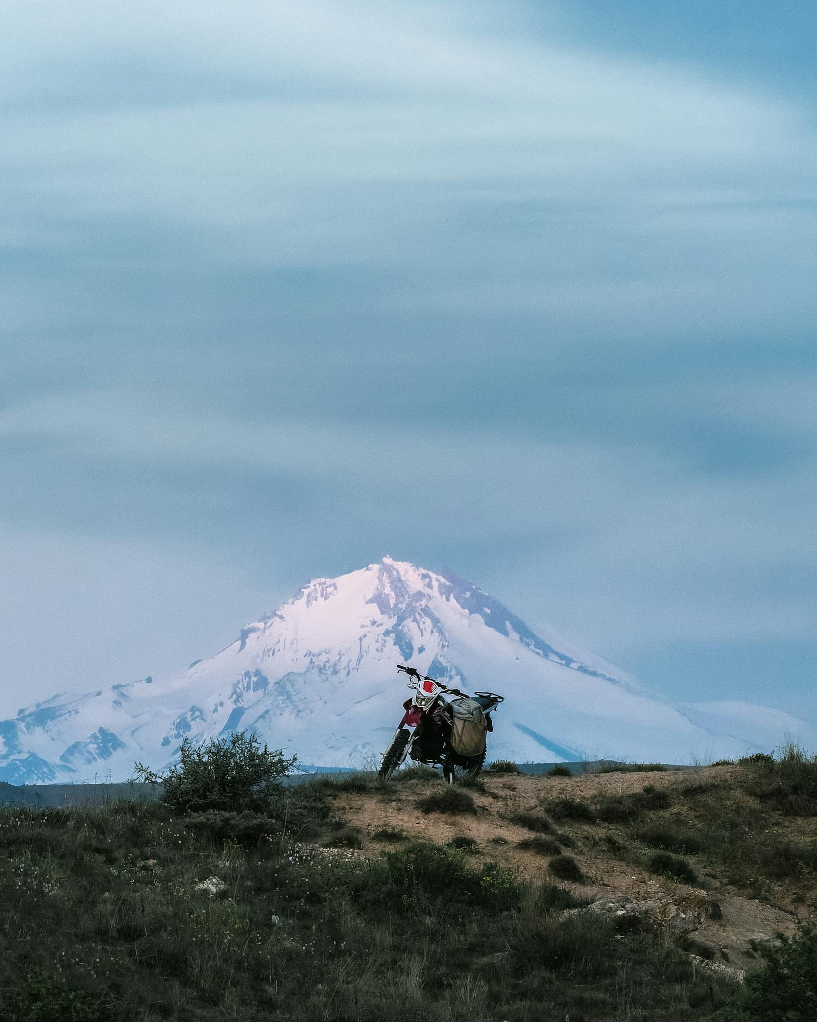 A motorcycle parked on a trail with a snowy mountain in the background, set in Türkiye's beautiful landscape.