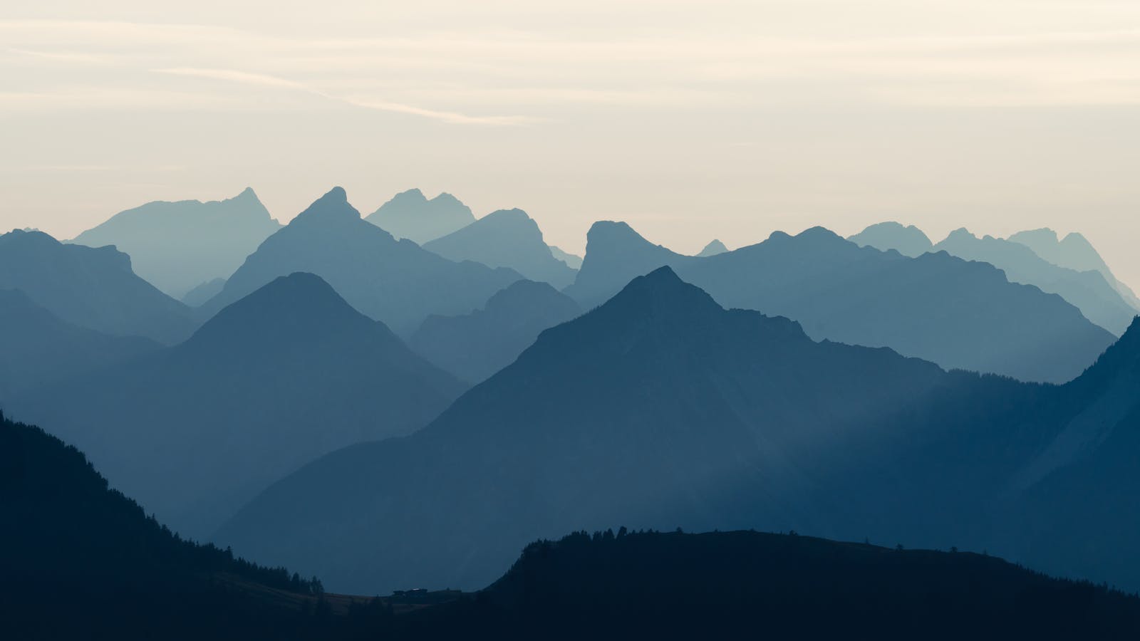 Serene view of layered mountain peaks creating a silhouette against the twilight sky.