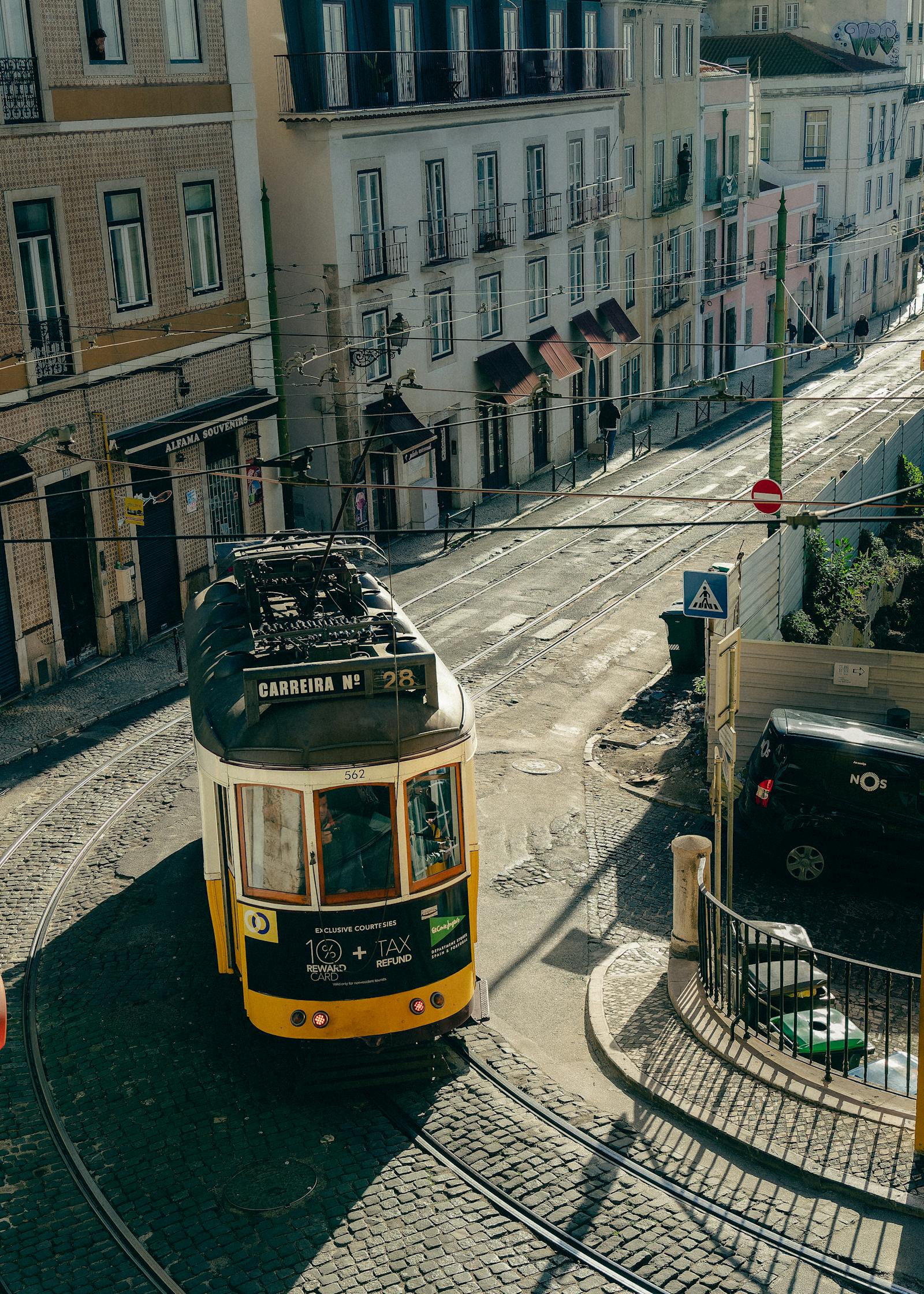 A classic tram traverses the charming streets of Lisbon, Portugal, under bright daylight.