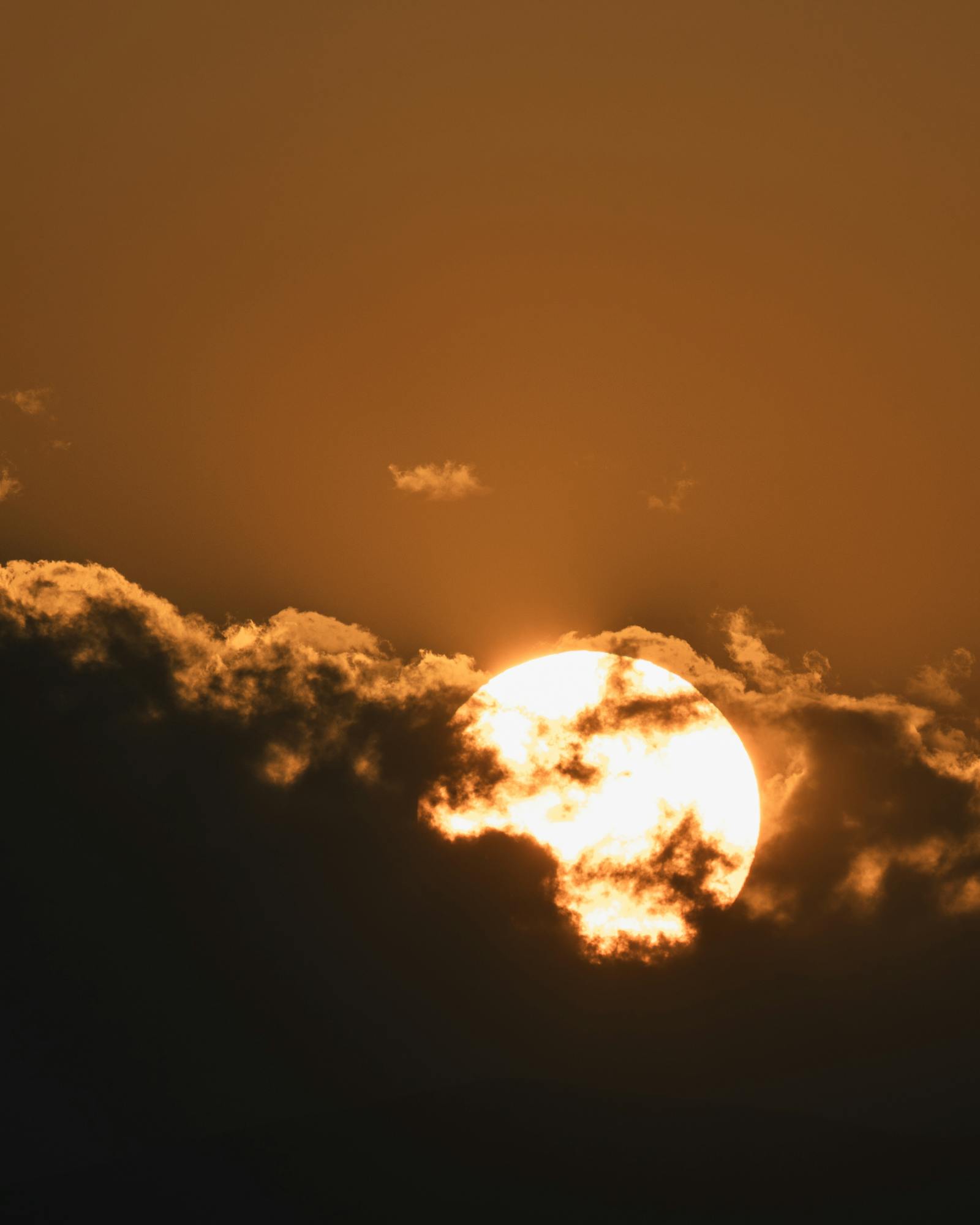 A stunning sunset with dramatic clouds partially obscuring the sun, creating a moody atmosphere.