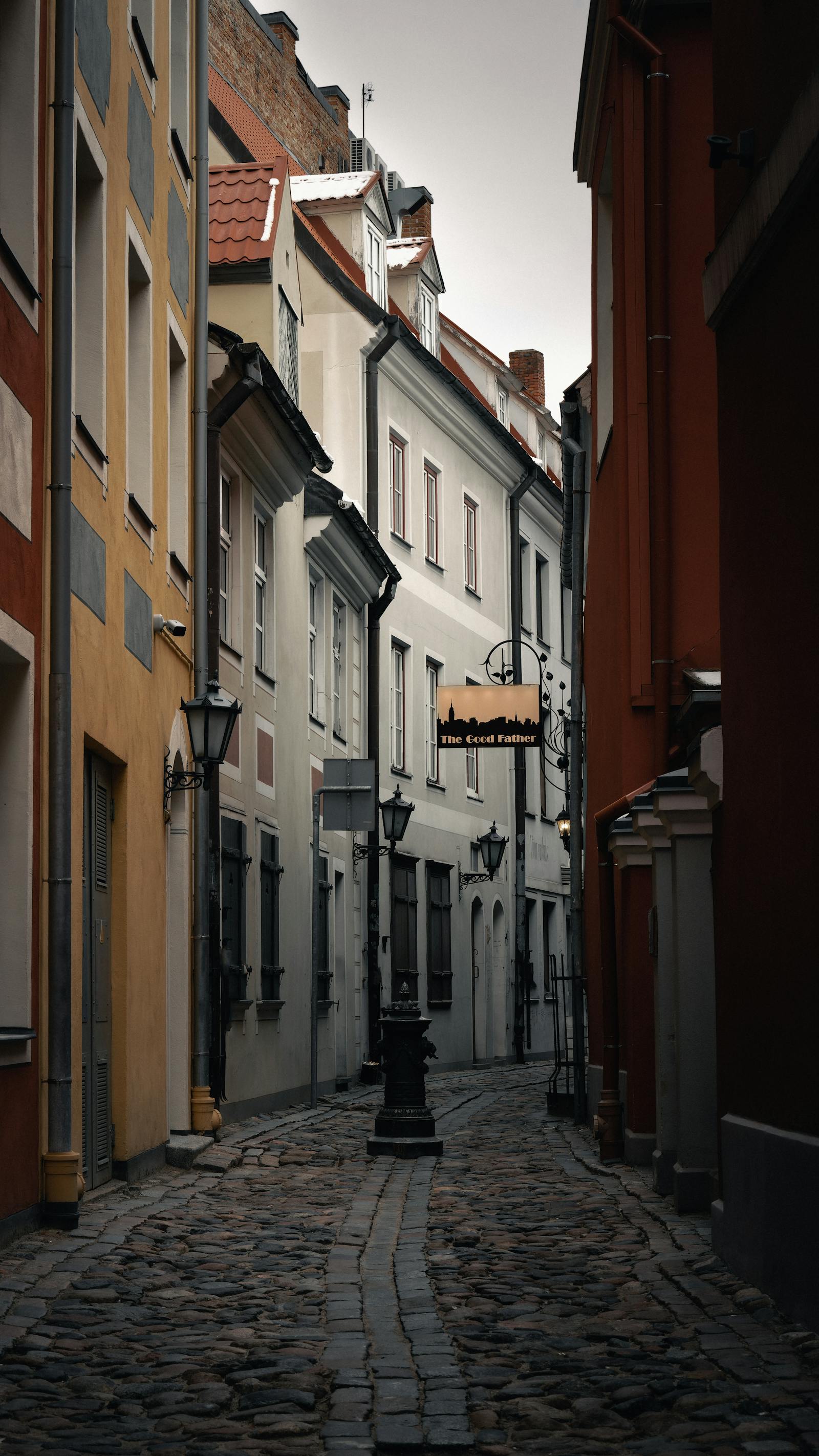 Narrow cobblestone alley in Old Riga with historic buildings and vintage street lamps