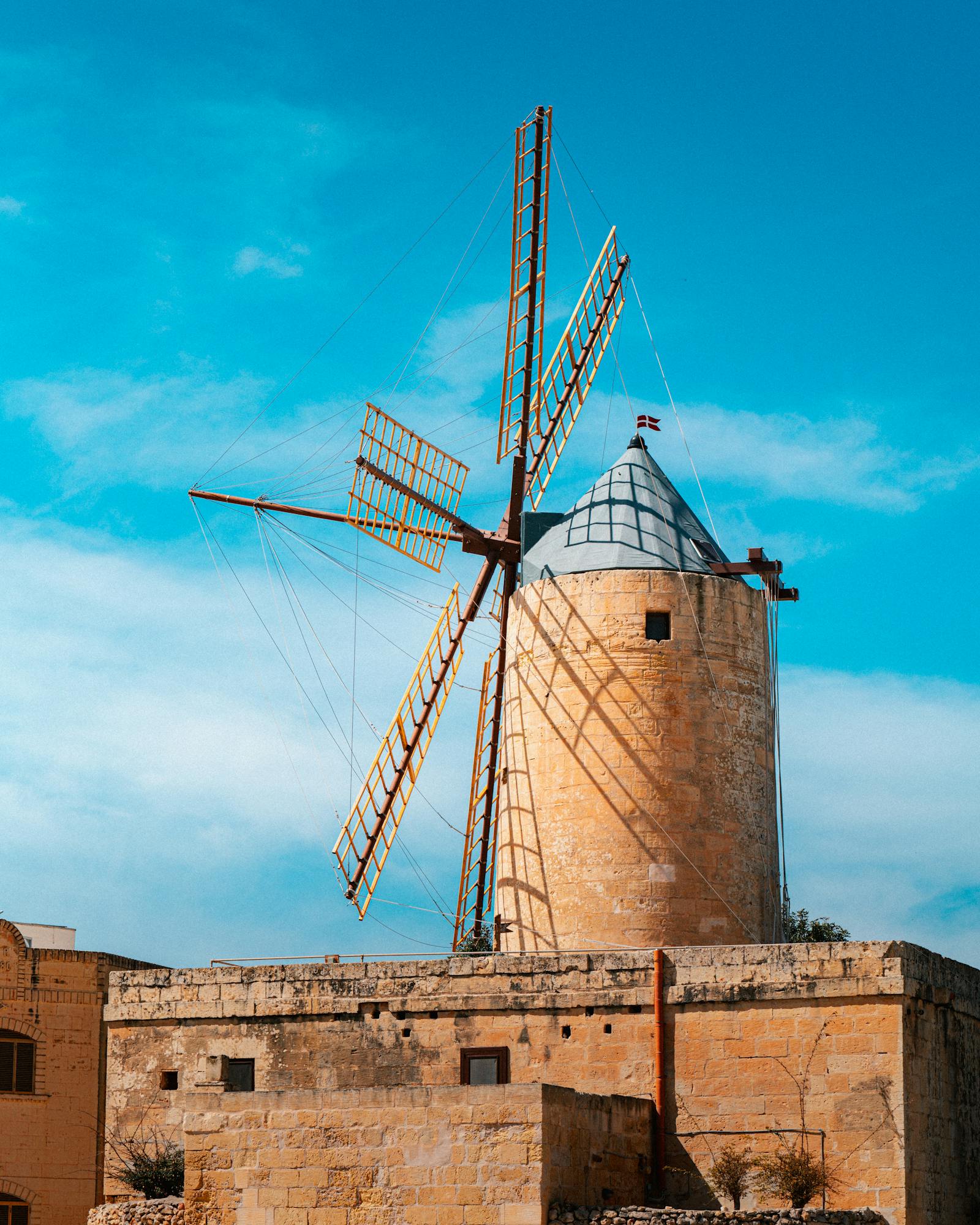 Charming old stone windmill in Malta under a bright blue sky, perfect for travel and history themes.