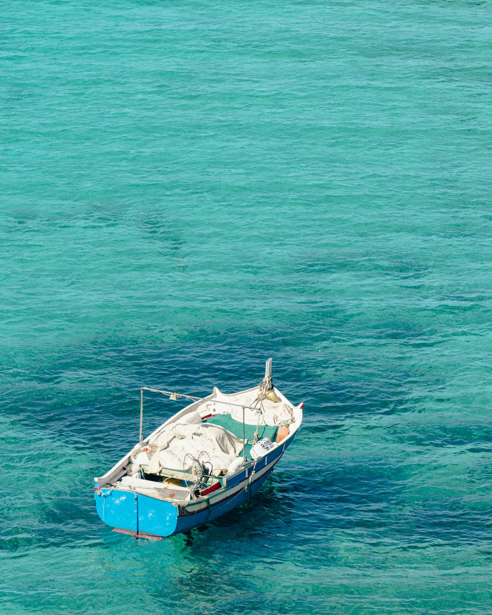 A solitary boat floats on the clear, blue waters of Malta, capturing tranquility and beauty.