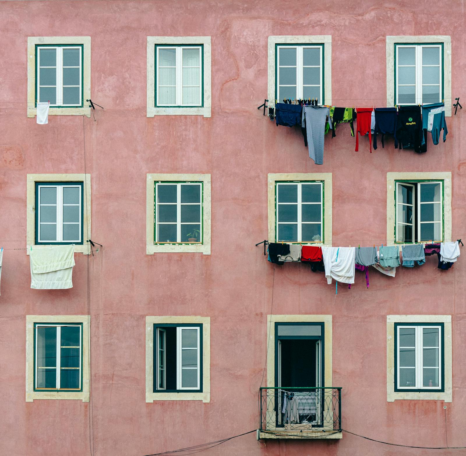 Pink building facade in Lisbon with hanging laundry and white-trimmed windows.