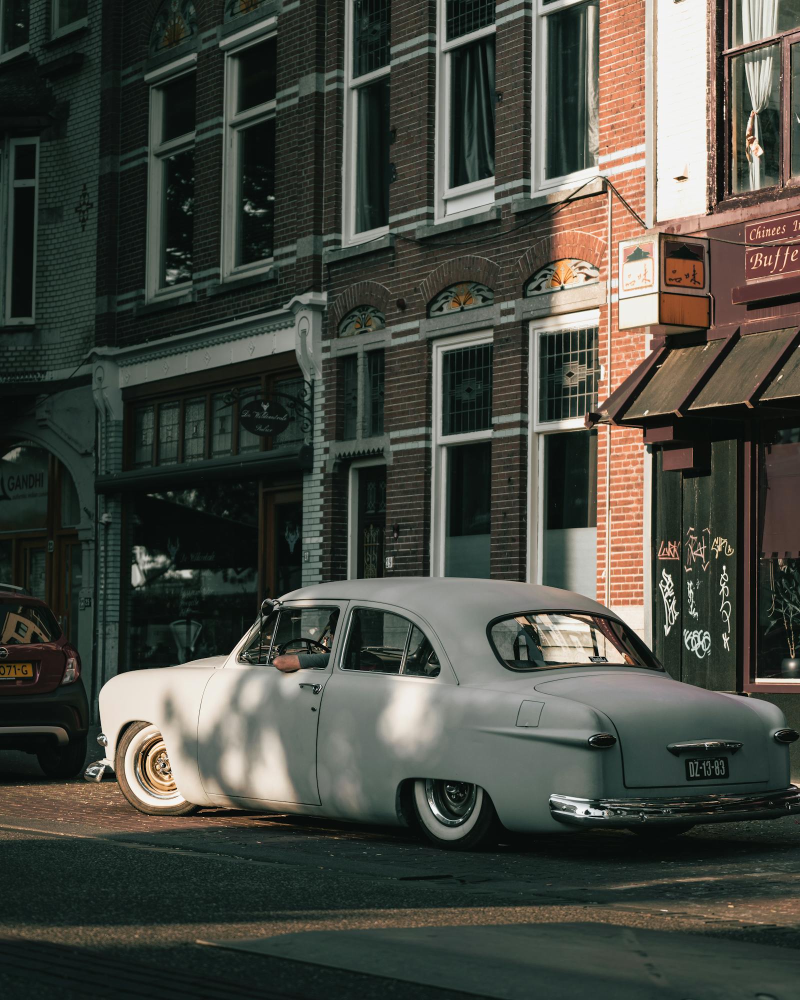 Classic white vintage car parked on a charming urban street with historic architecture.