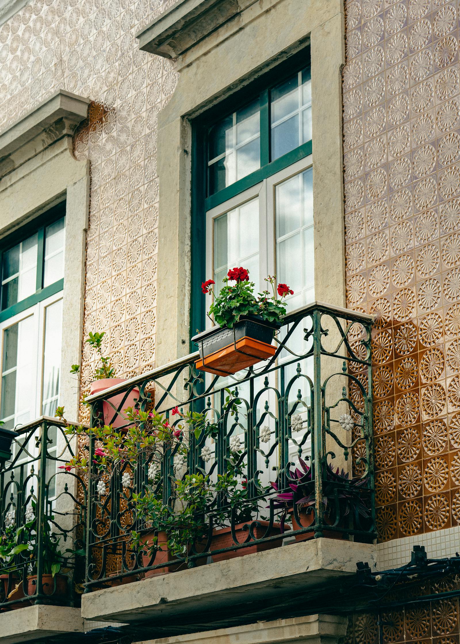 Charming residential balcony adorned with vibrant flowers and wrought iron railing in an urban setting.