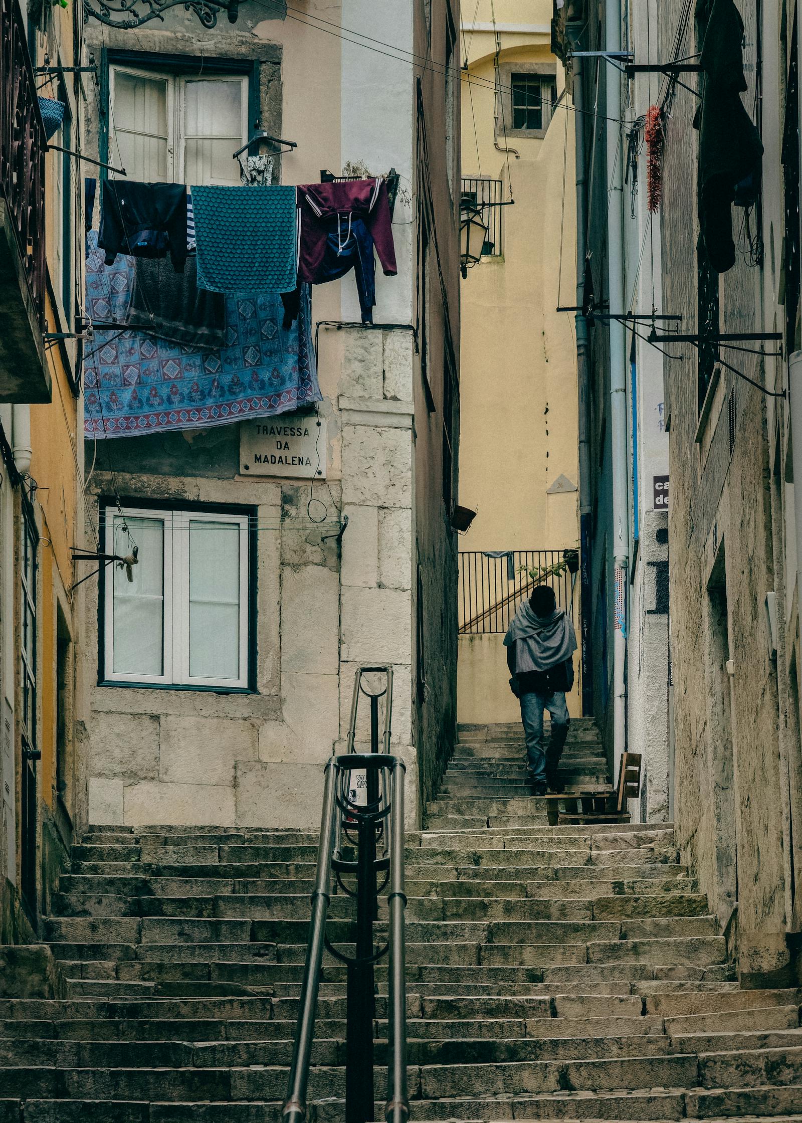 Explore a picturesque narrow staircase in Lisbon's historic district with hanging laundry and worn stone steps.