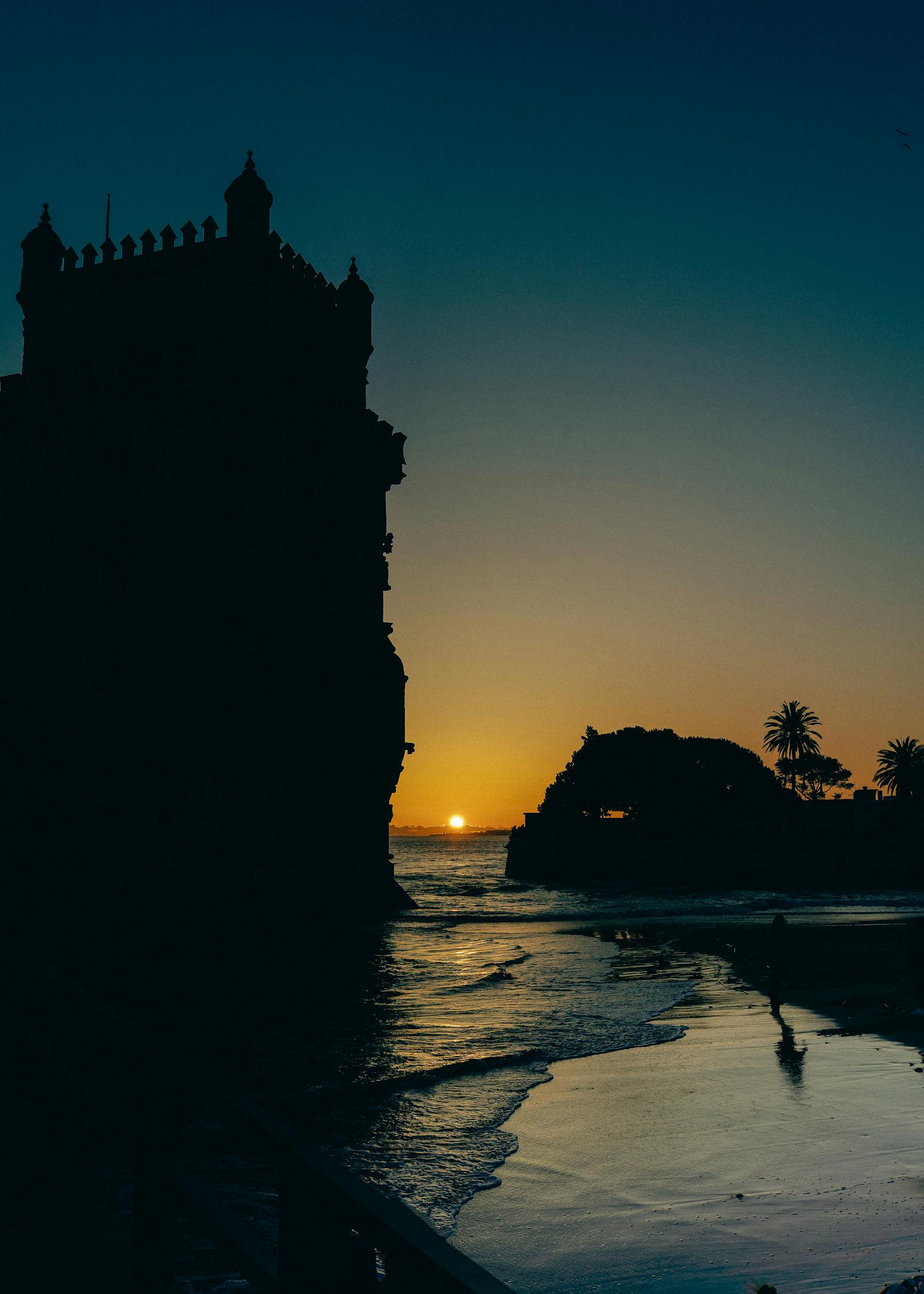 Captivating sunset silhouette of Belém Tower by the river in Lisbon, Portugal.