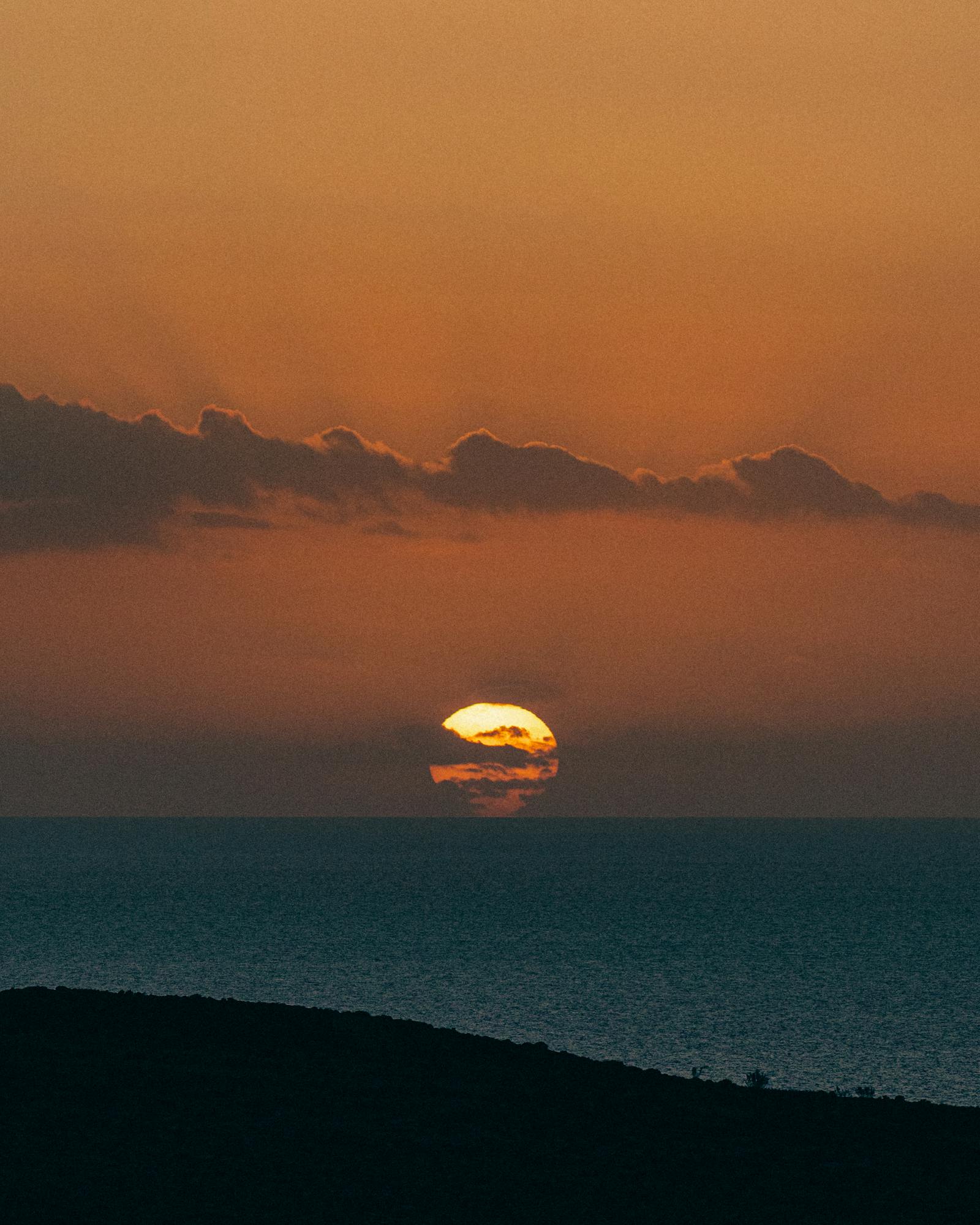 Capture the breathtaking sunset view over Mellieħa, Malta with a vibrant sky and serene sea.