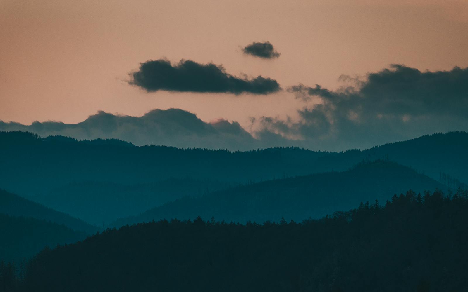 Silhouetted mountain range at dusk in Graz, Austria, with moody clouds.