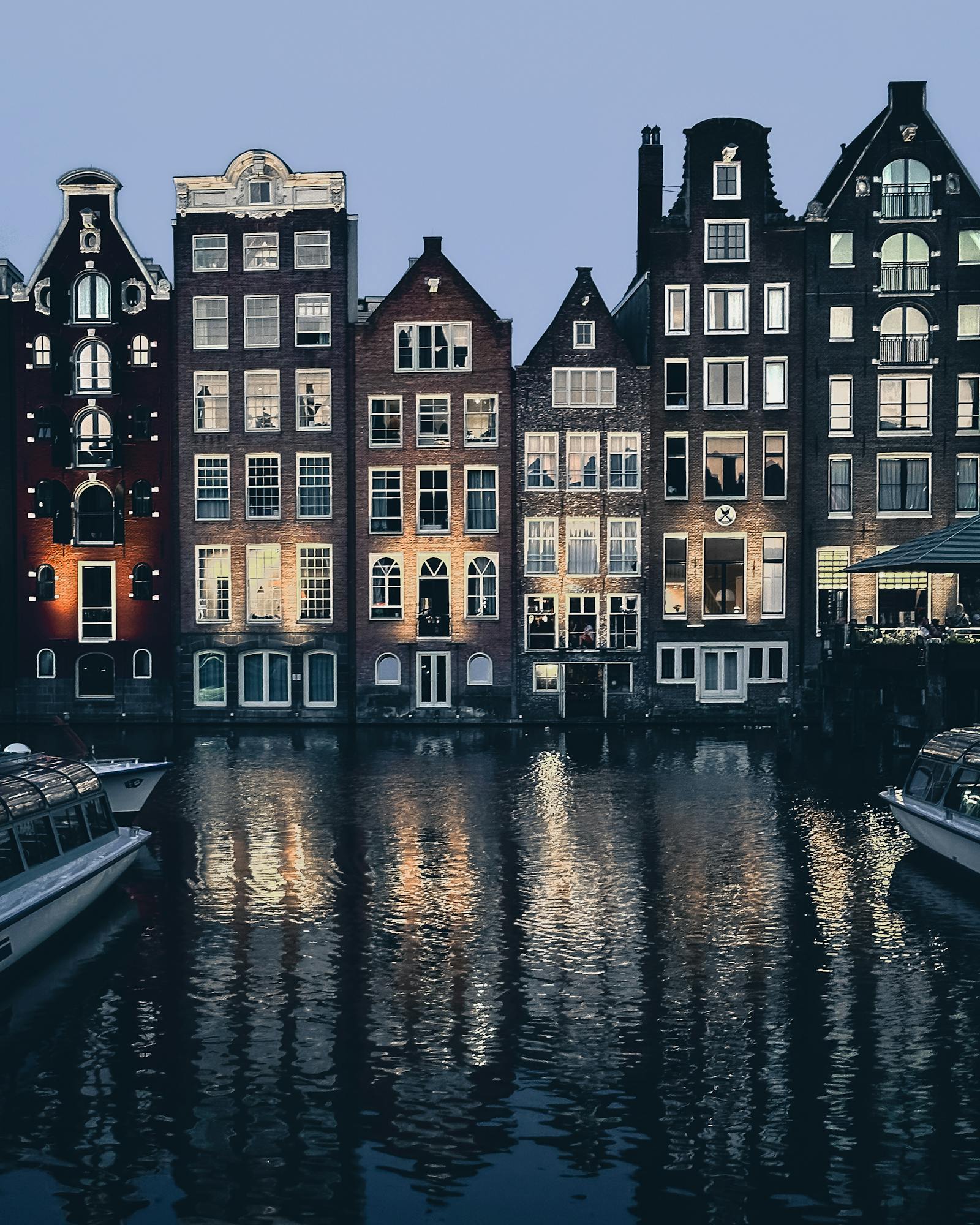 Beautiful view of traditional Amsterdam canal houses reflecting on water at twilight.