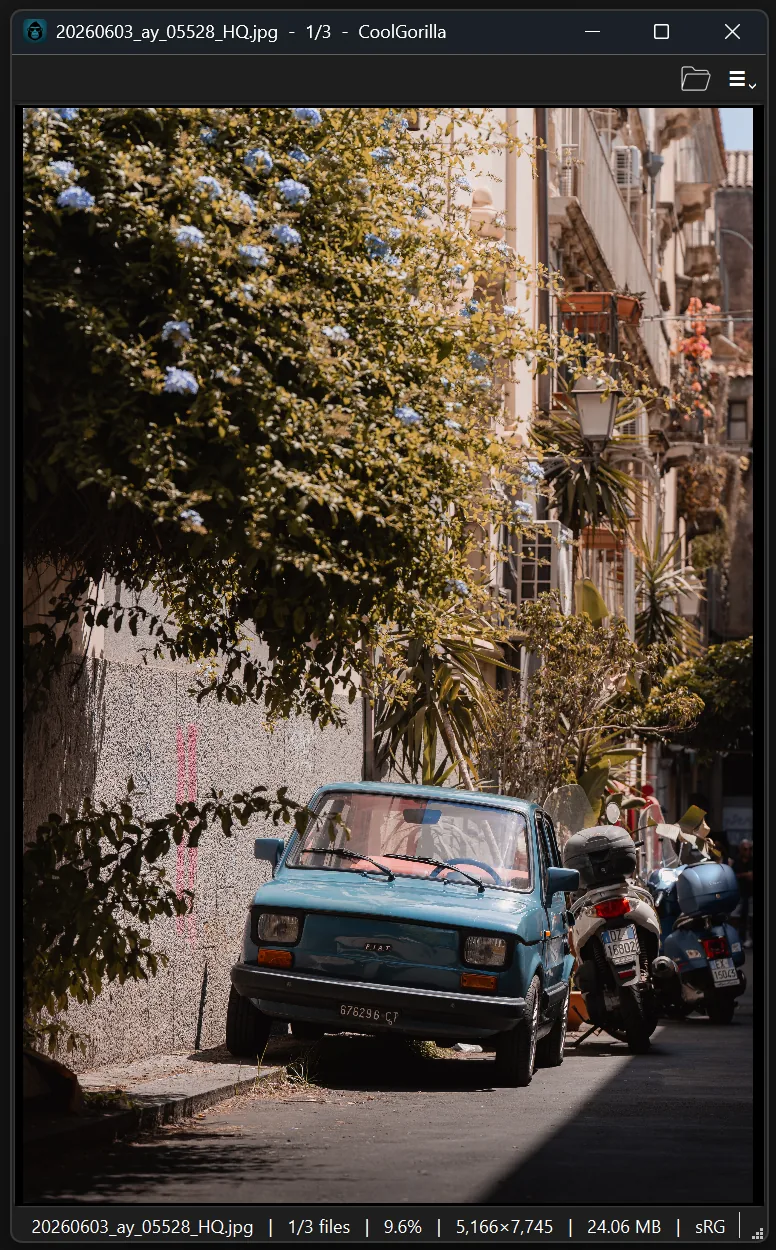 A narrow portrait CoolGorilla window showing a blue car on a Sicilian street